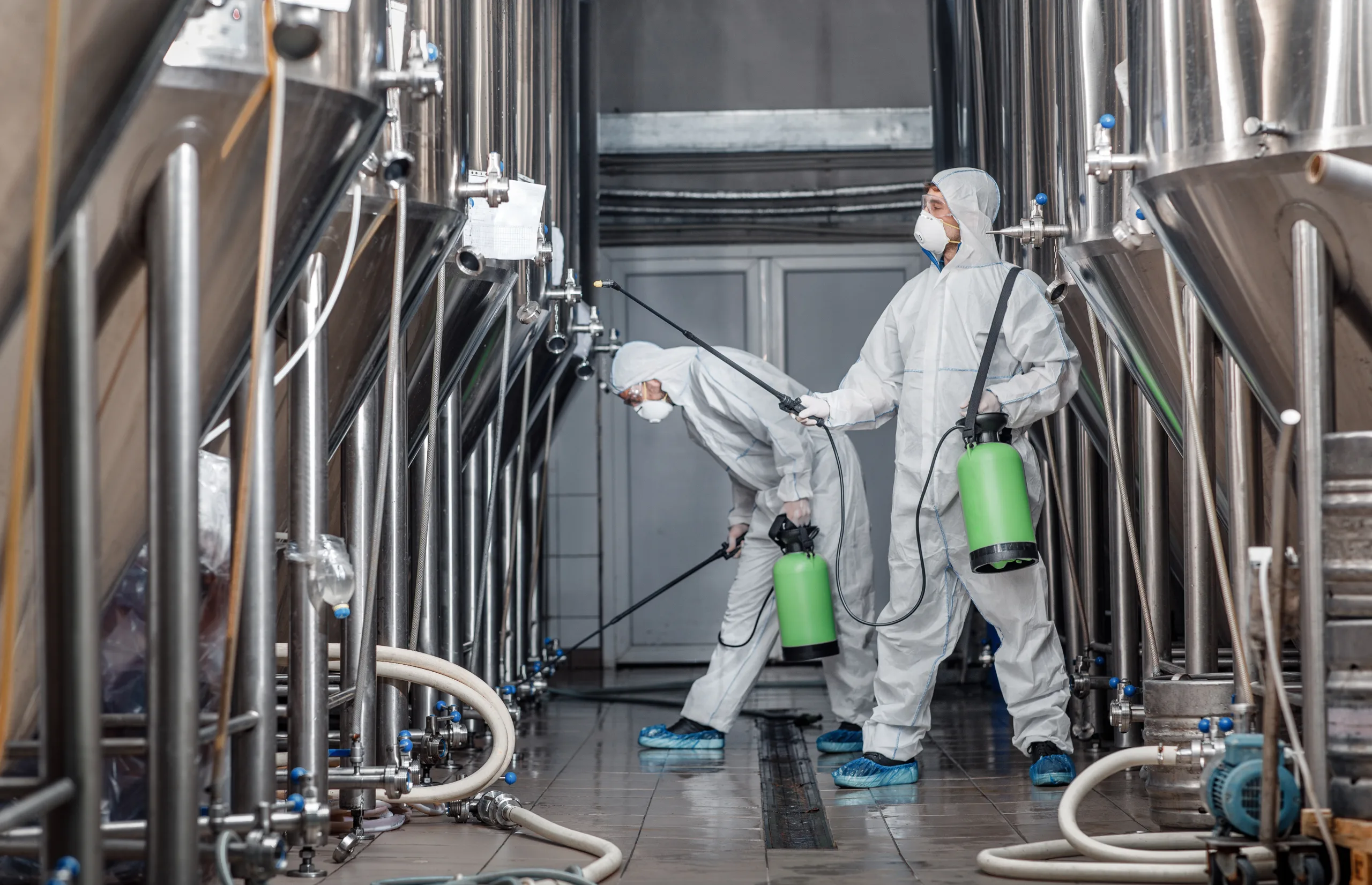 Craft brewery, eco product and disinfection. Workers in hazmat suits clean plant professional cleaning scaled