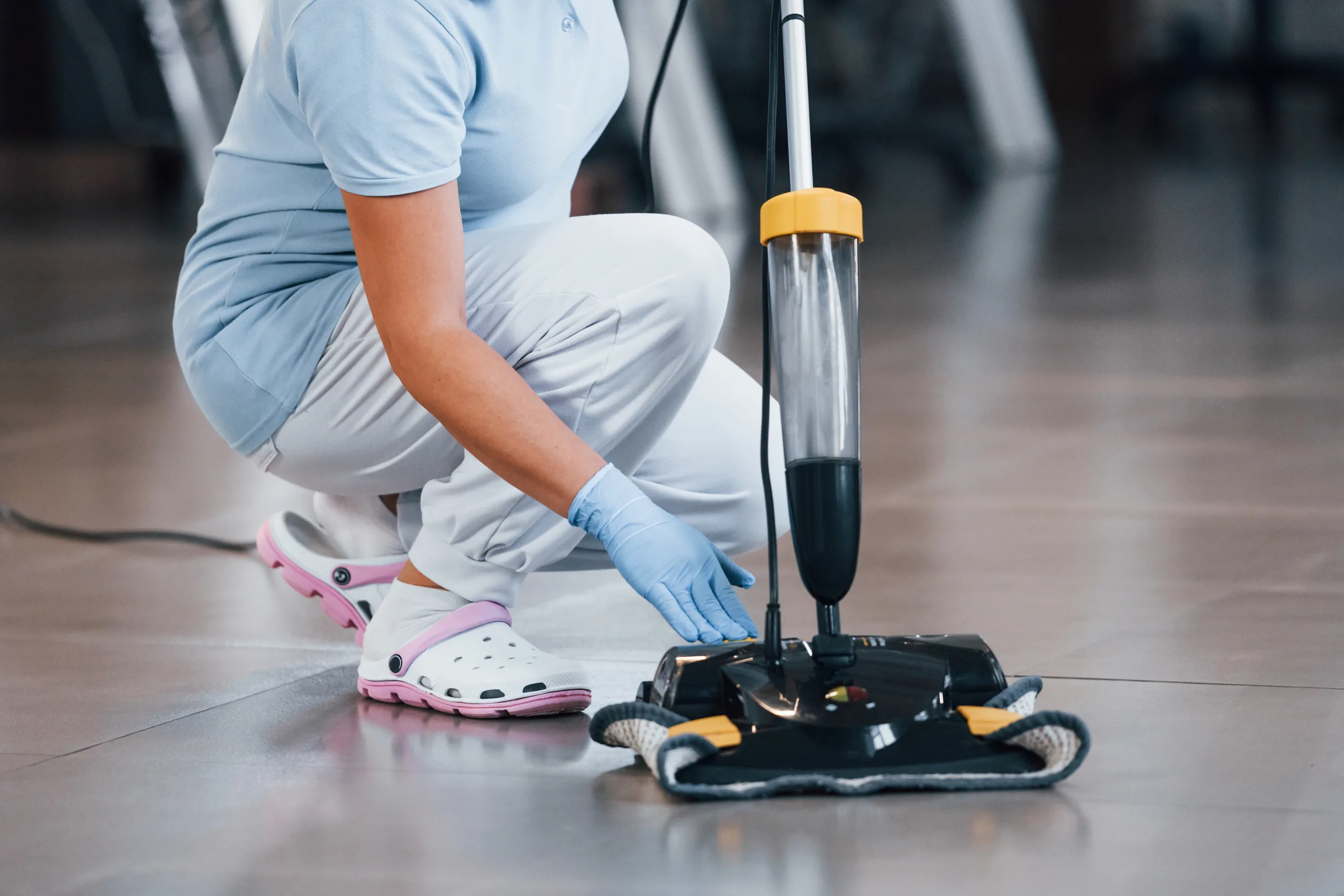 Close up view of woman that uses vacuum cleaner indoor in modern office floor cleaning scaled