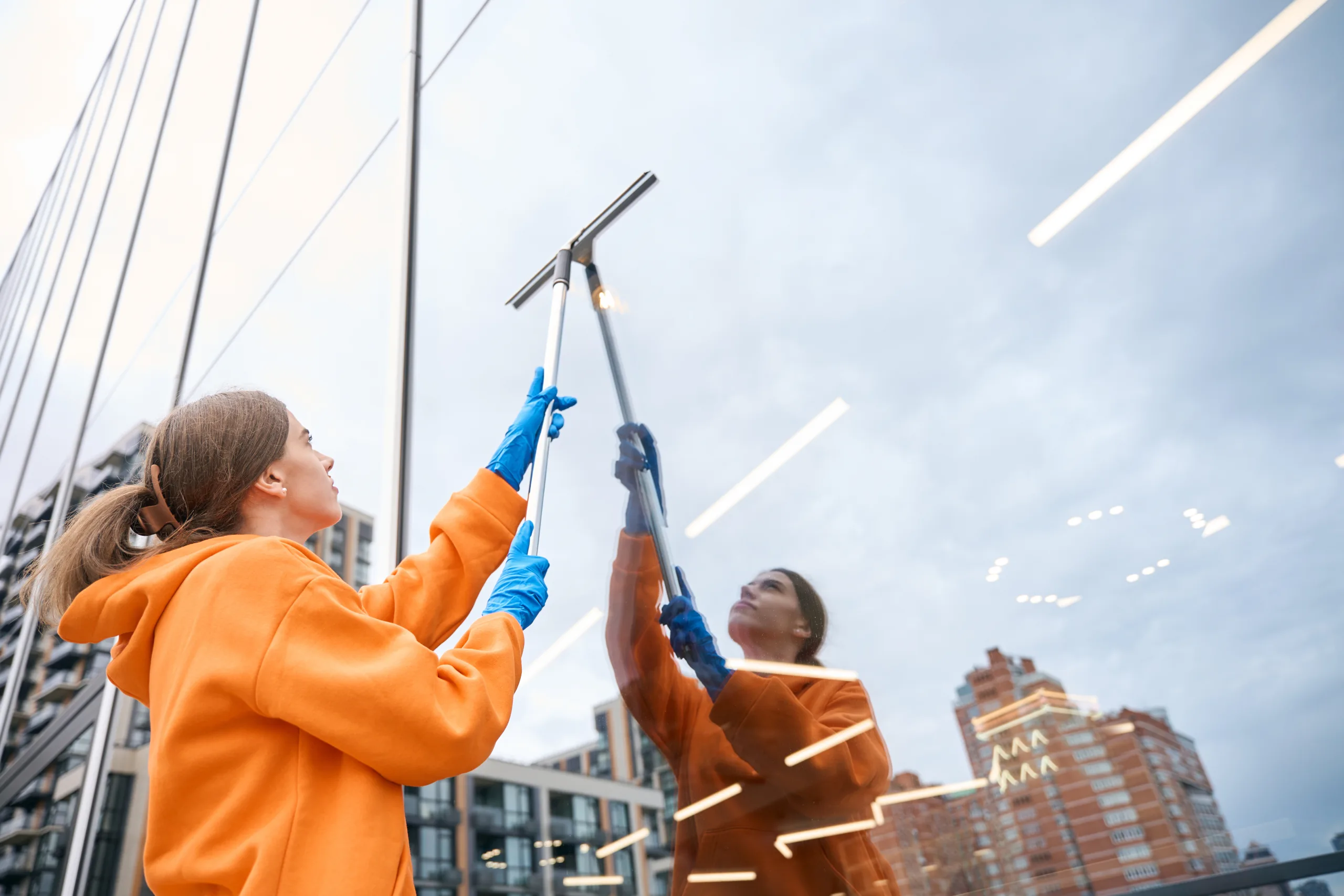 Cleaning lady washing windows with window cleaning mop glass cleaning scaled