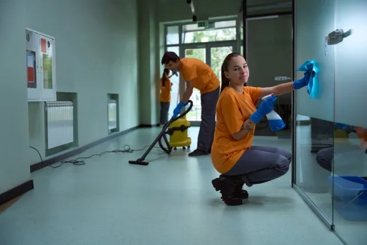 Team of cleaning professionals in matching orange uniforms