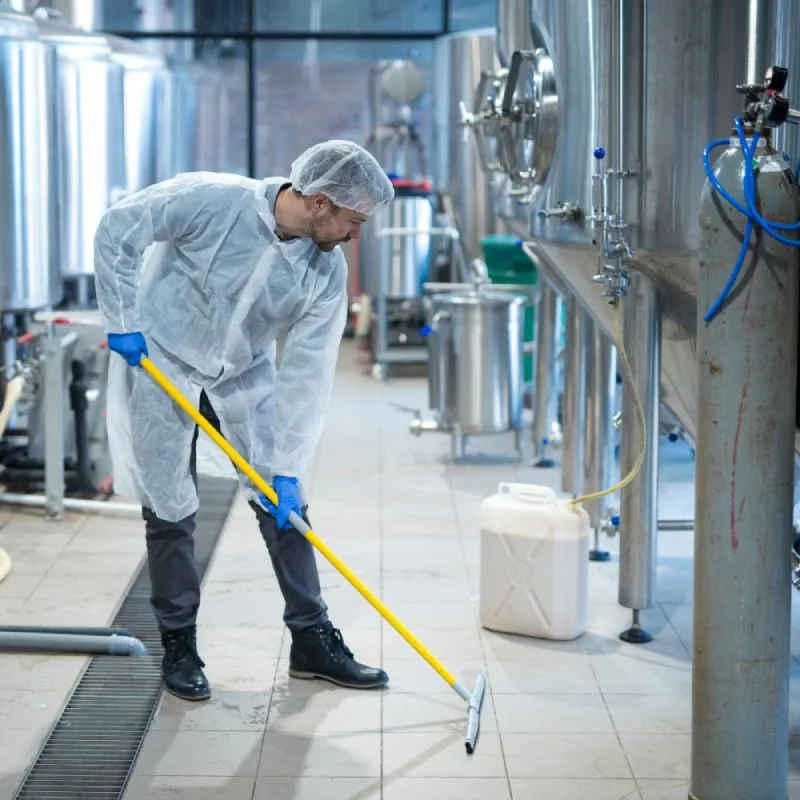 Professional cleaner using an industrial-grade scrubber for warehouse floor degreasing in Phoenix.